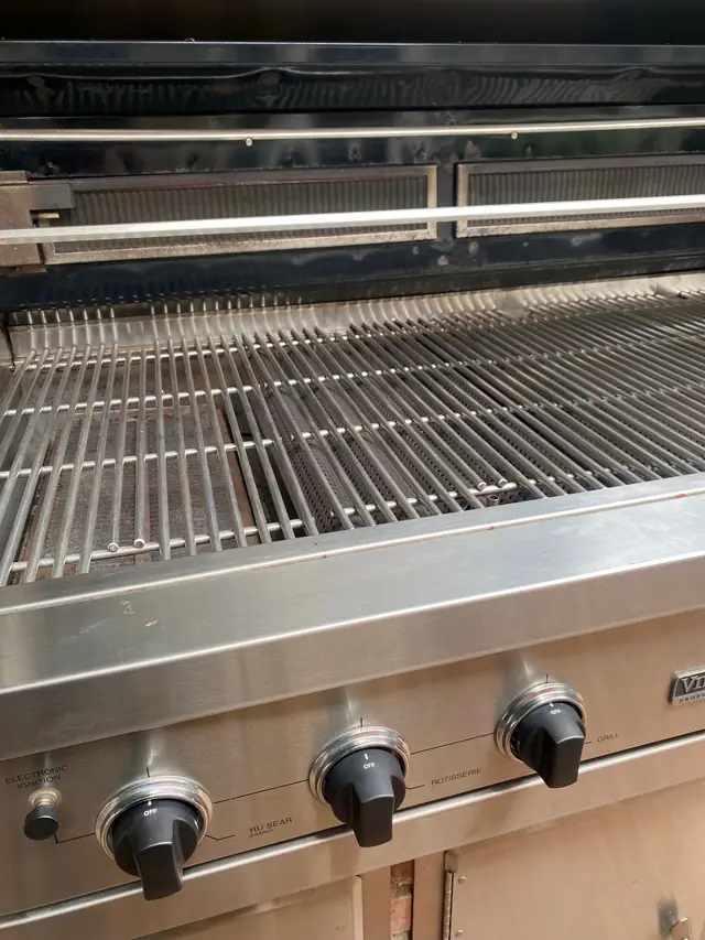 Close view of clean cooking grates above a row of control knobs