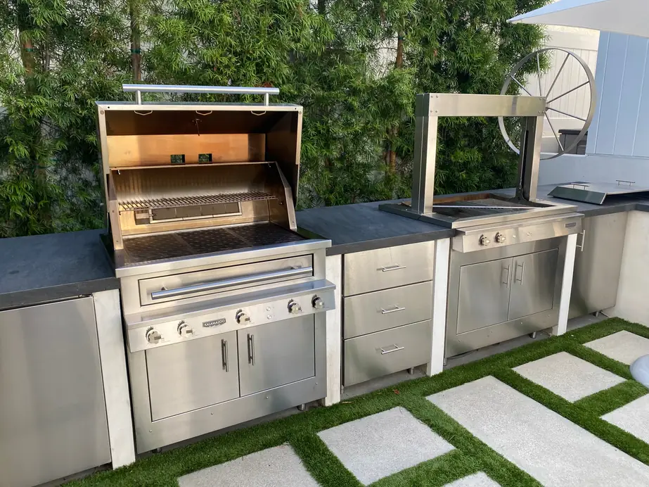 Built-in stainless grill run in an outdoor kitchen with the hood open, after a deep clean