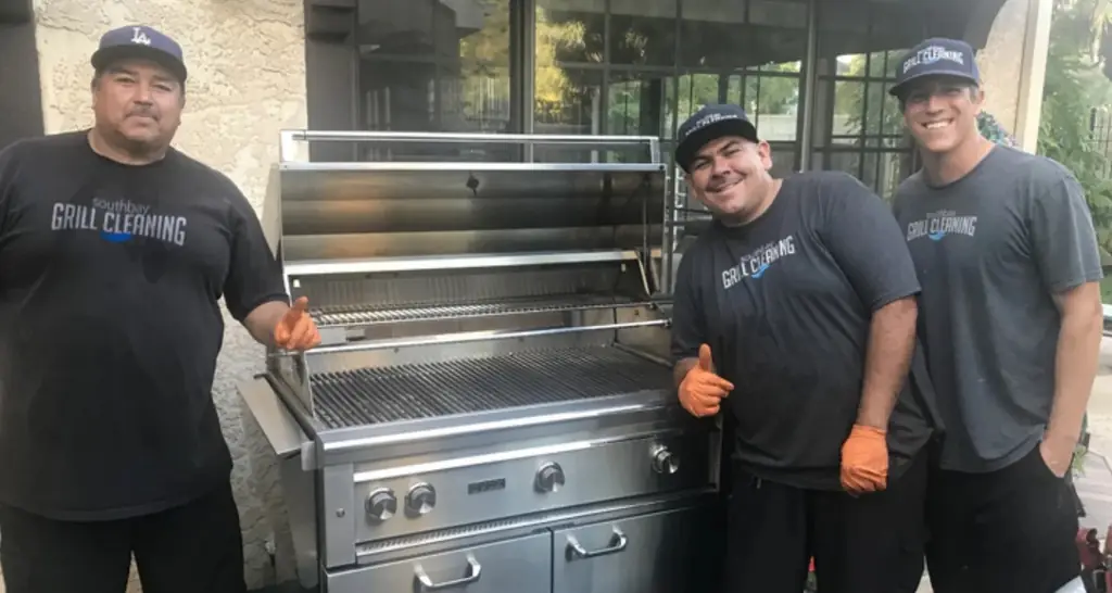 Three South Bay Grill Cleaning crew members in branded shirts and caps beside a finished stainless grill